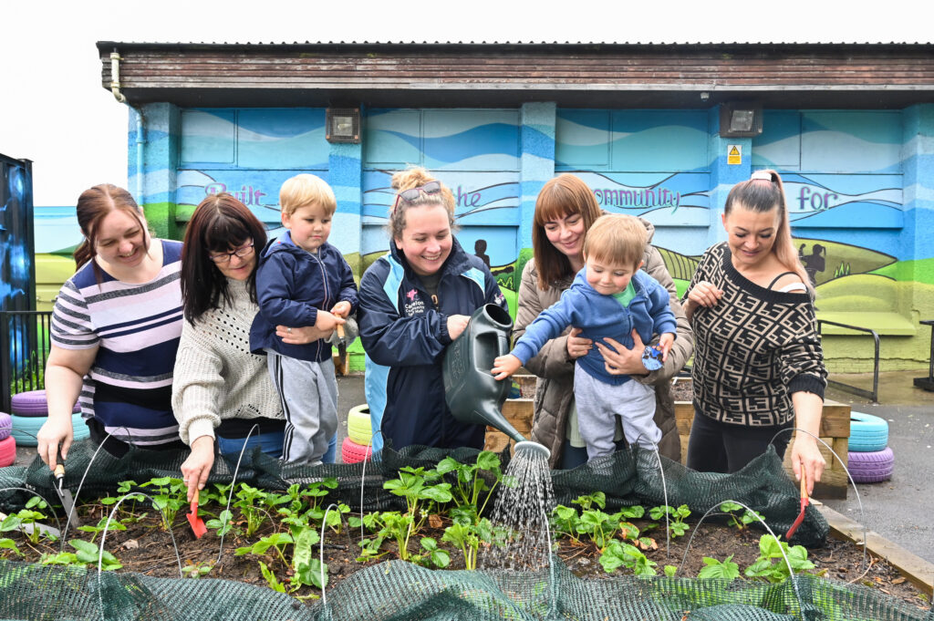 Falkirk Food Futures Preschool kids and their carers tend to the strawberry patch in the Community Garden strawberry patch at Tamfournill Community Centre.