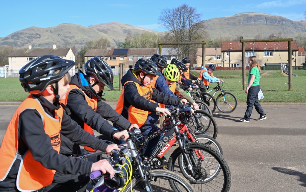 A group of children standing with their bikes and ready to start cycling, on a bright day.