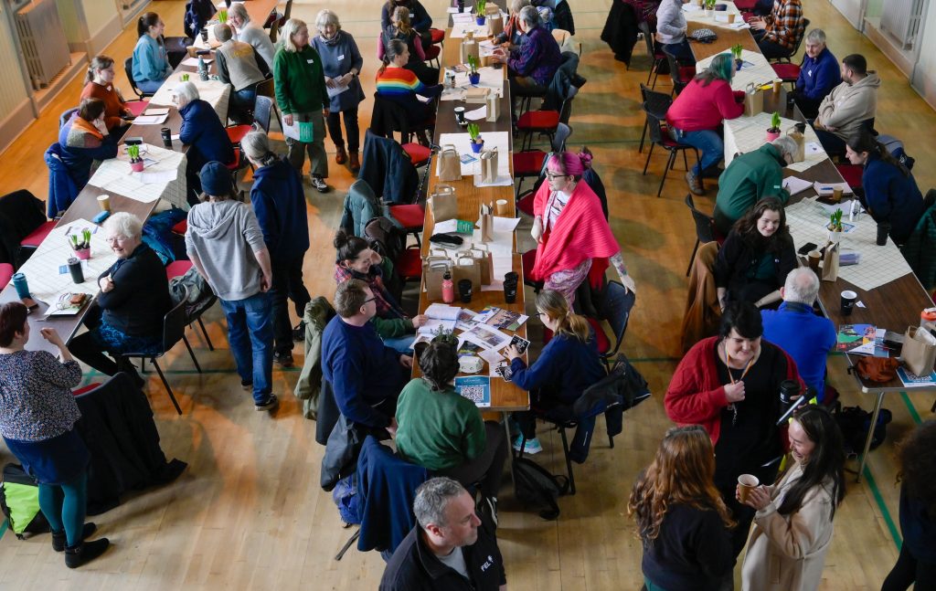 A photo taken from above of around 30 people having lunch on long tables