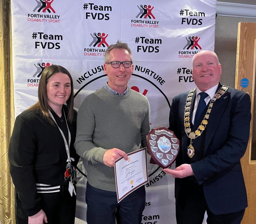 Three people standing together and hold the Clackmannanshire Inspire Award. Drew Taylor (FEL Scotland), Carly Lauder (Clackmannanshire Council) and Donald Balsillie (Provost of Clackmannanshire Council) are the three people.