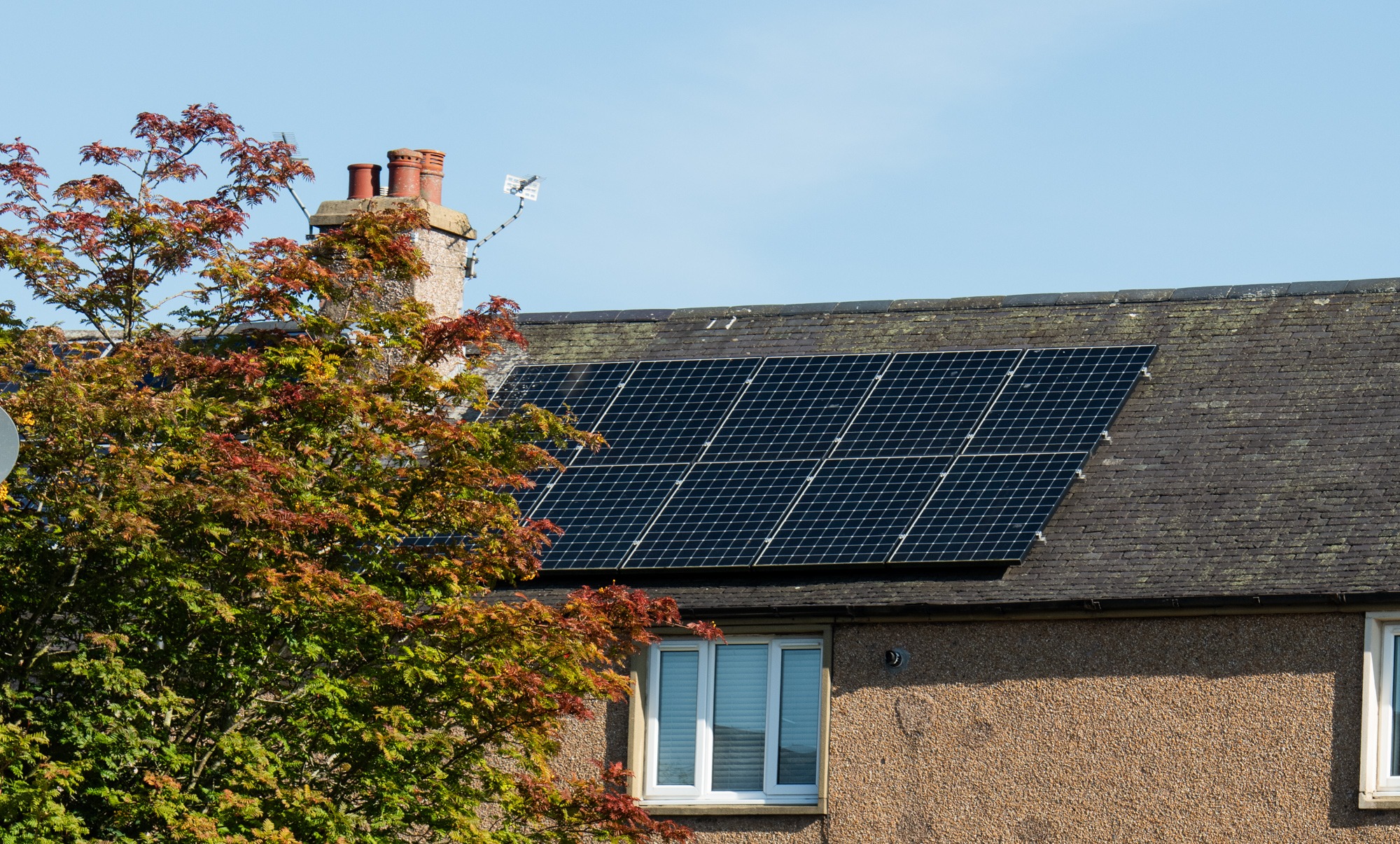 A close-up photo of solar panels on the roof of a house on a bright day